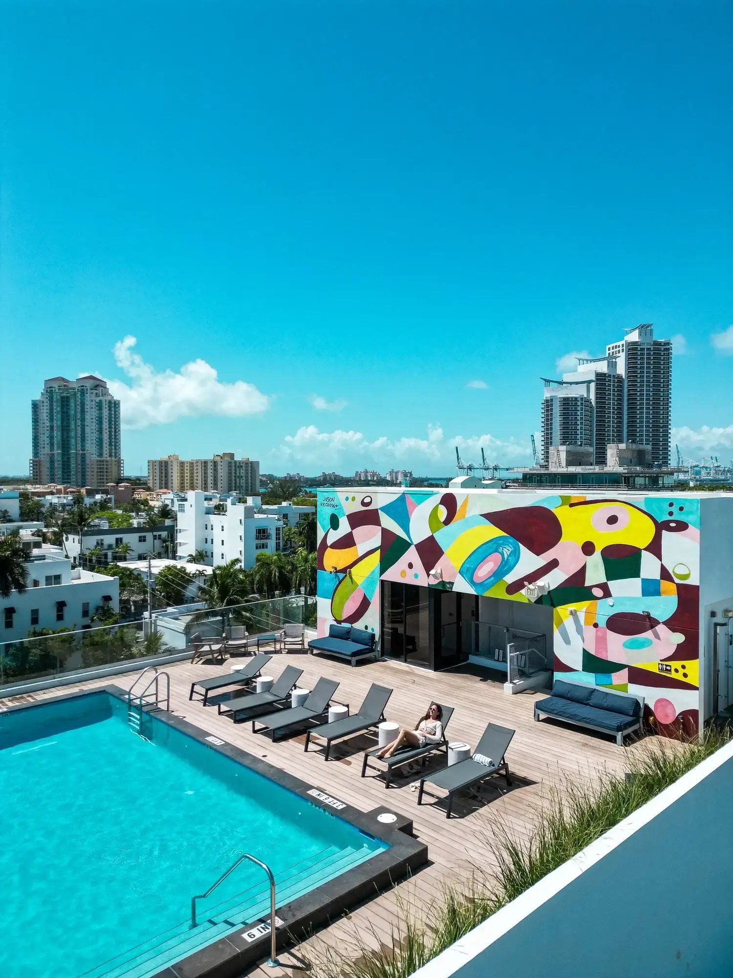 Guest relaxing on a poolside lounge chair on a rooftop sundeck overlooking the Miami Beach skyline at Hotel Upsun