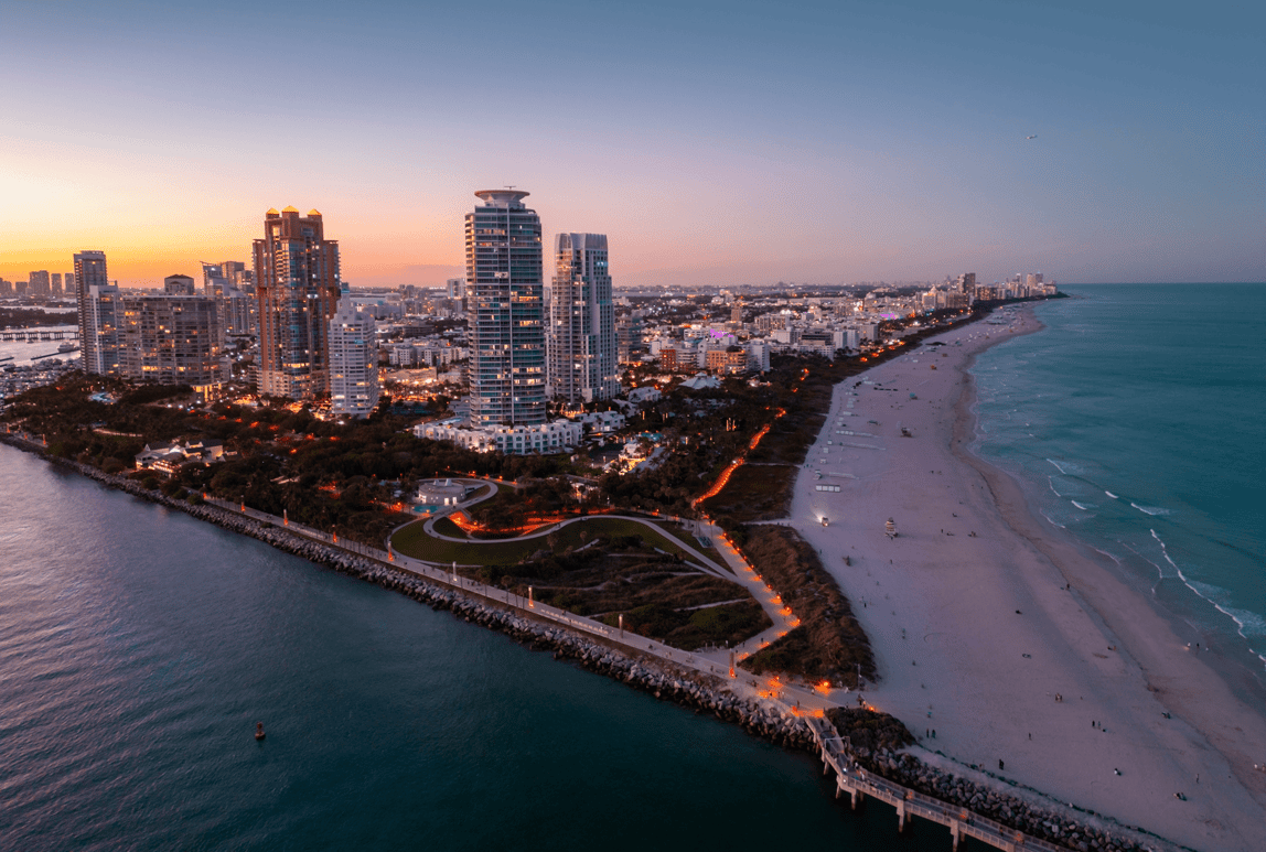 Aerial view of South Beach Miami skyline and jetty at sunset, with high-rise condos and Atlantic Ocean coastline