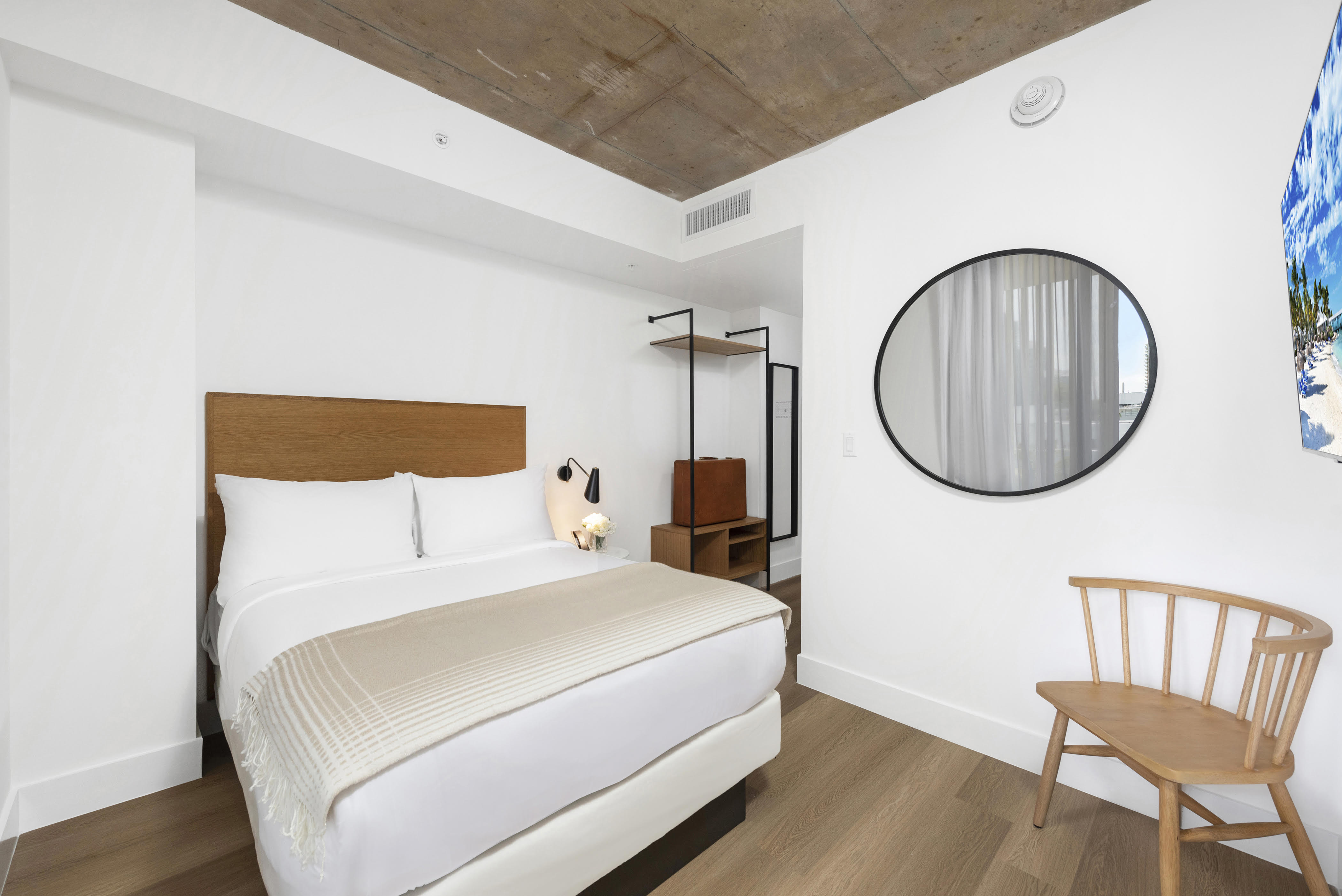 A modern hotel room with a bed, chair, and mirror